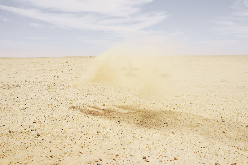 A desert landscape with a cloud of dust floating in the air