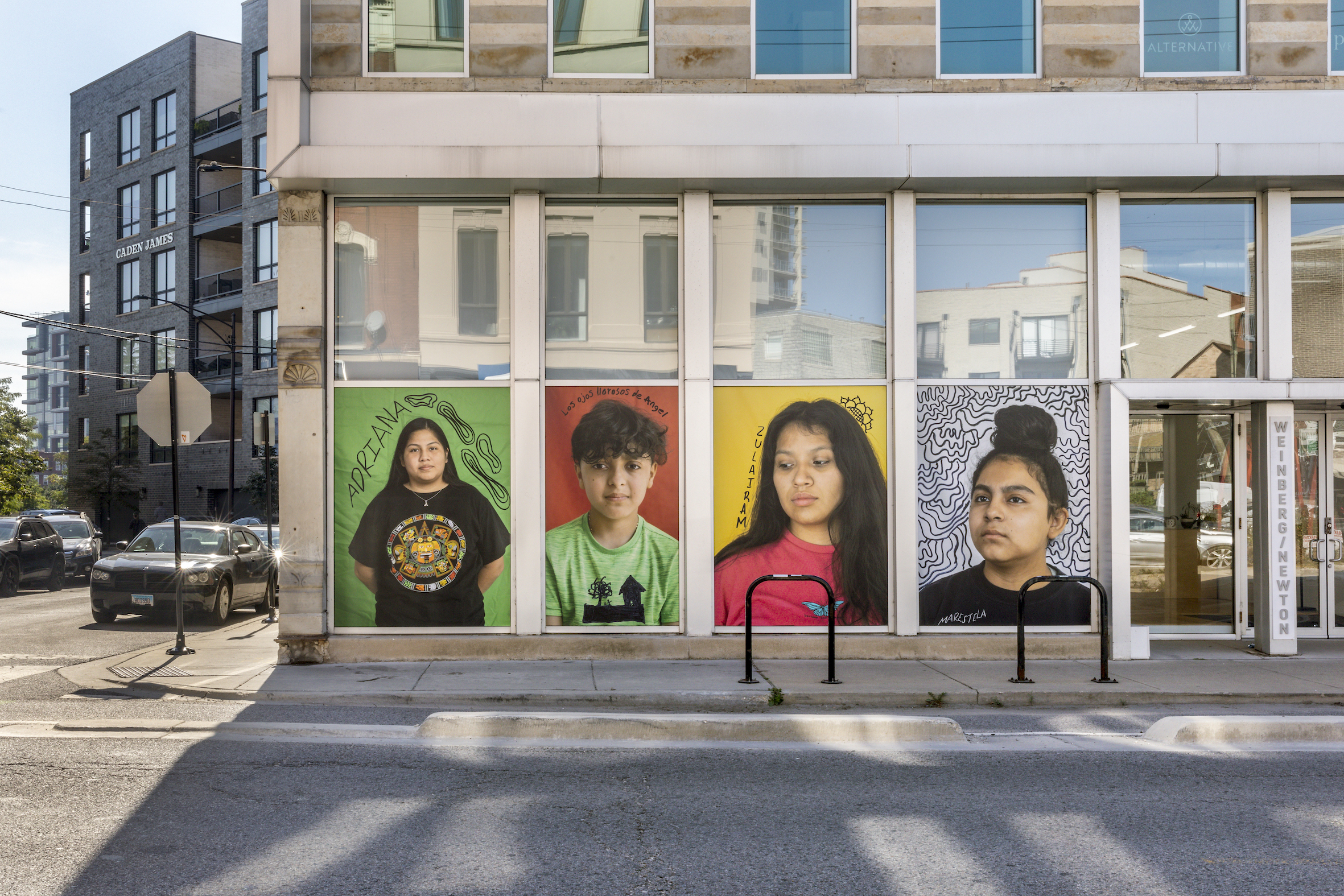 An exterior photograph of the Weinberg/Newton Gallery, Chicago, showing four portrait photographs by Wendy Ewald displayed in the gallery windows.