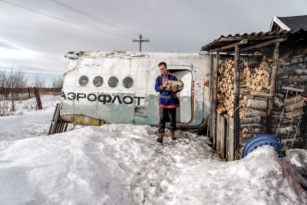 A man carries wood from the wreckage of an airliner which he uses as a hangar.