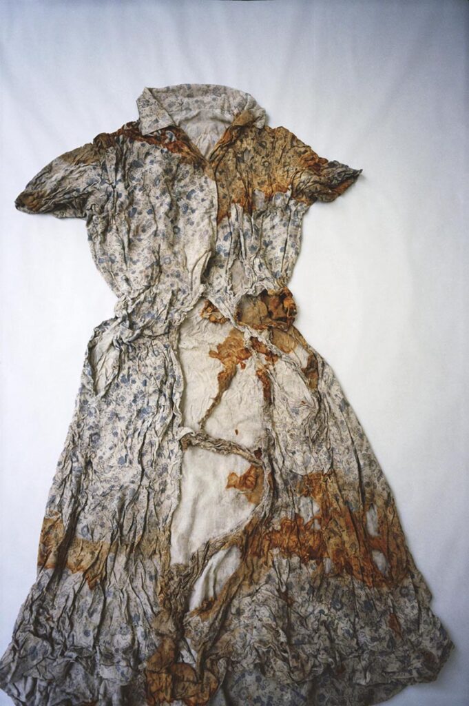 A torn, stained white dress with a blue pattern.