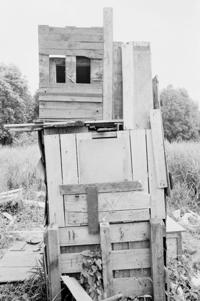 Black and white image depicting wooden planks nailed into a house-like structure.