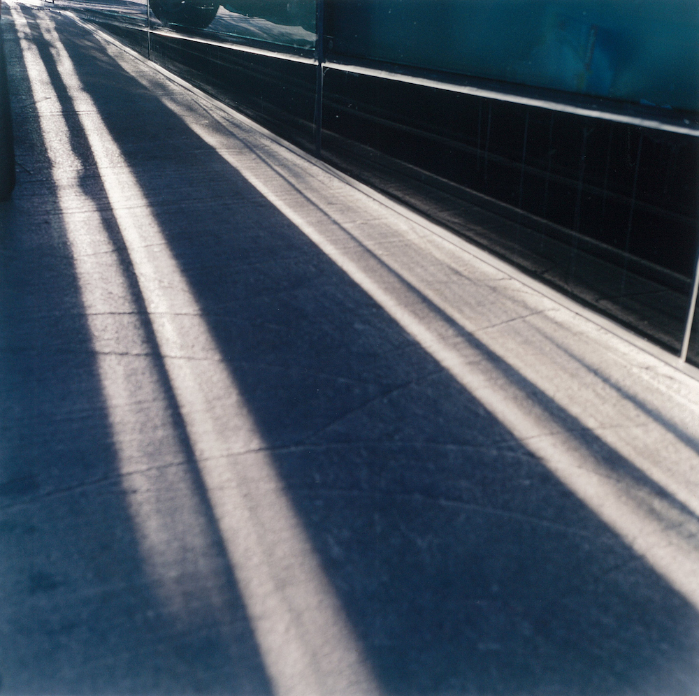 Colour photograph depicting rays of sunlight on a pavement.