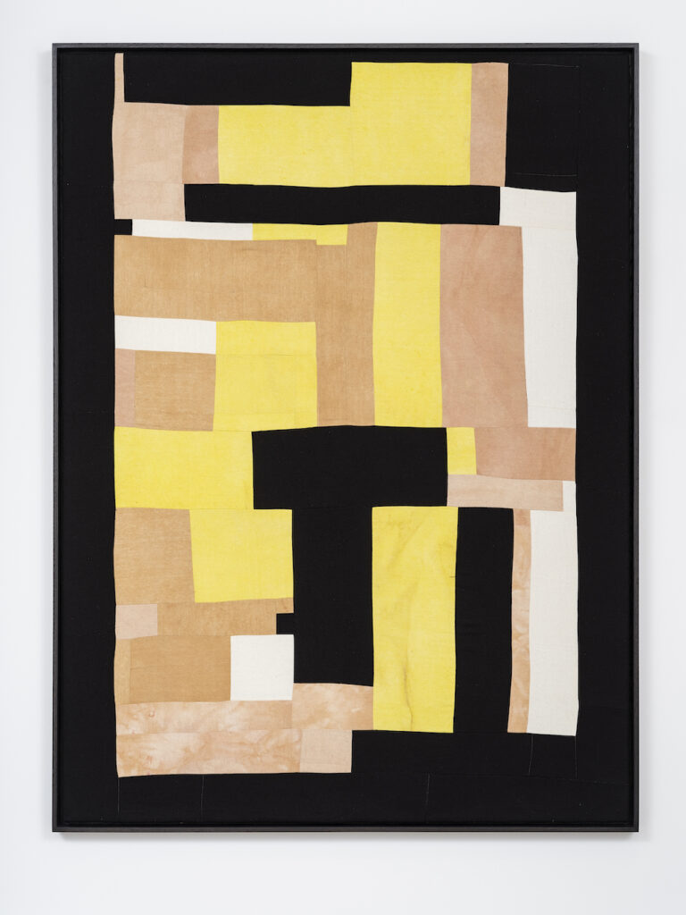 Fabric collage by Yto Barrada. Squares in black, yellow, orange and white are arranged in a rectangle.