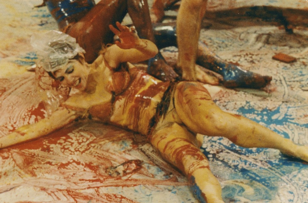 Performance of 'Meat Joy'. A woman rolls in red and blue paint.