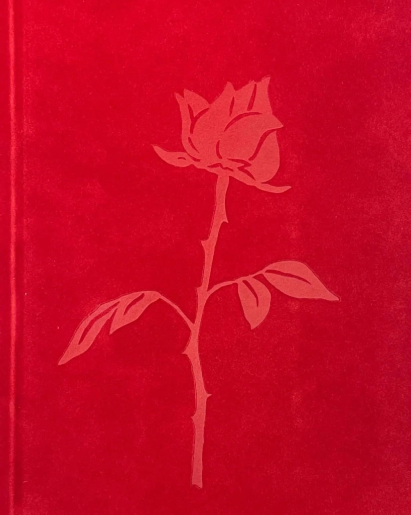 Colour image showing the cover of HER OWN. The cover is red velvet with an embossed rose illustration.