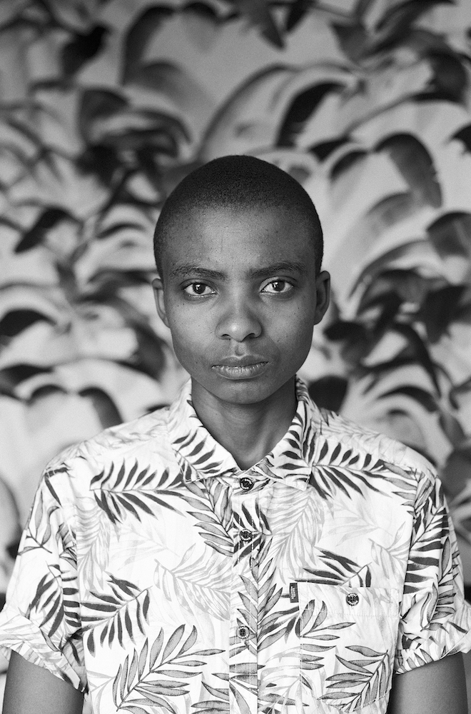 Black and white photograph. Portrait of a person wearing a shirt decorated with palm leaves.