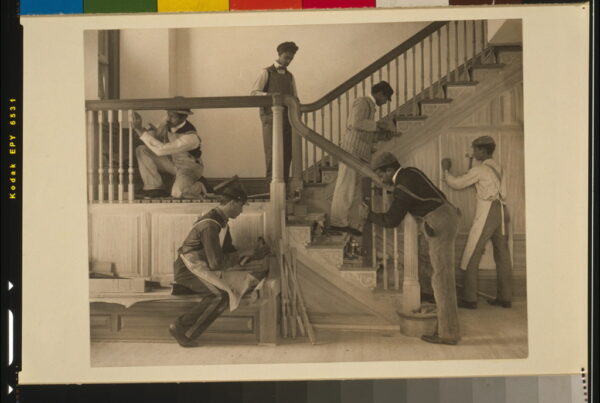 Black and white photograph (sepia toned) of a group of men building a staircase.