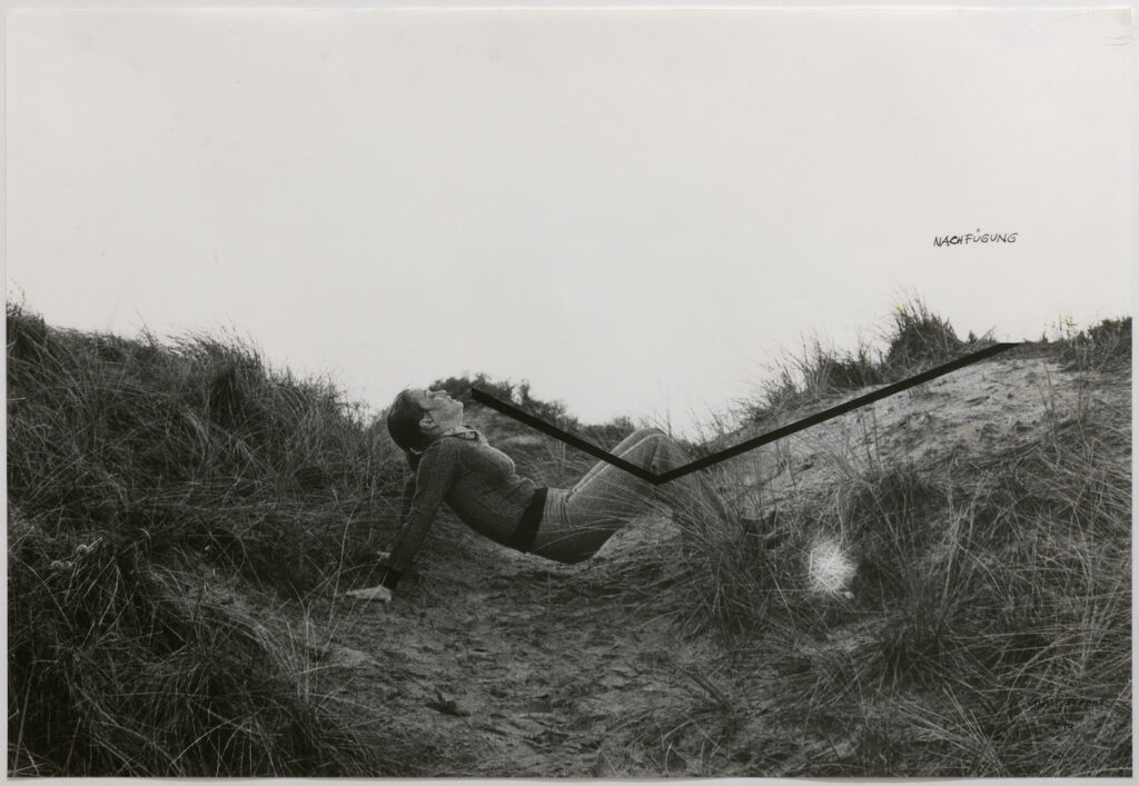 Black and white photo. A woman rests on her hands and feet in the dip of a sandy hill. A black line drawn on the image mimics her pose.