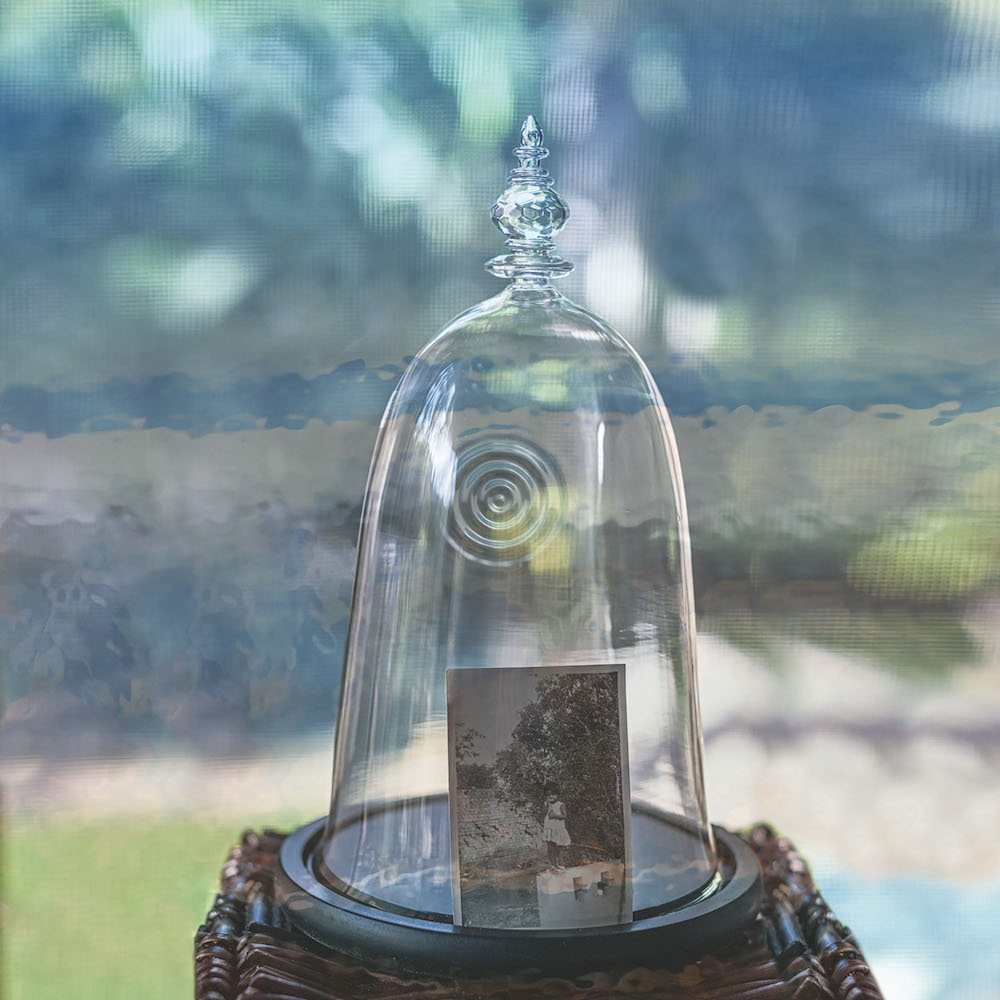 Colour photograph of a bell jar over a black and white photograph of a child.