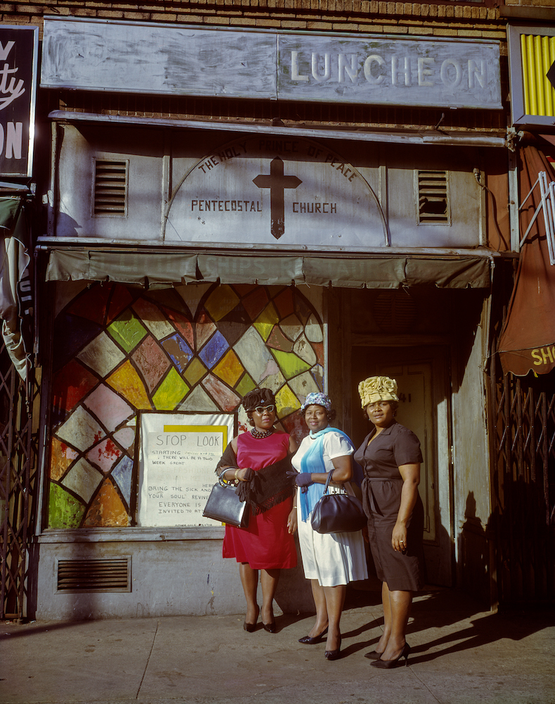 Colour photograph. Three women standing outside a church in Harlem.