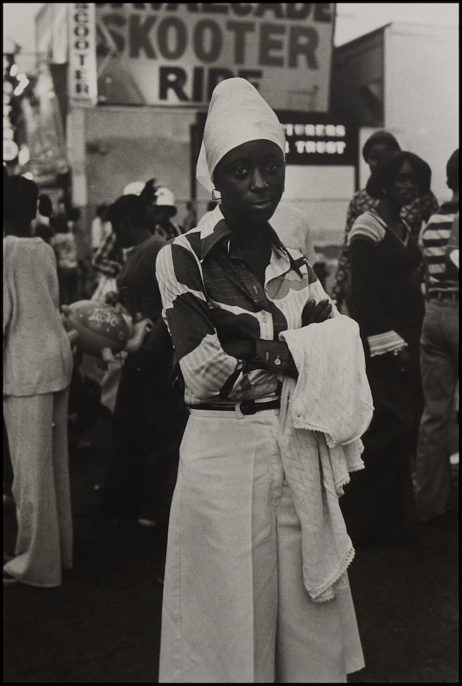 Black and white photo of a woman in a white hat and skirt.