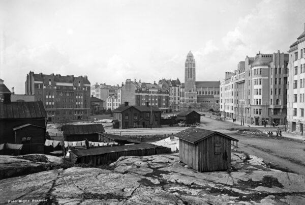 Black and white photo of Helsinki in 1912. Wooden buildings stand in front of a larger expanse of buildings, constructed with bricks.
