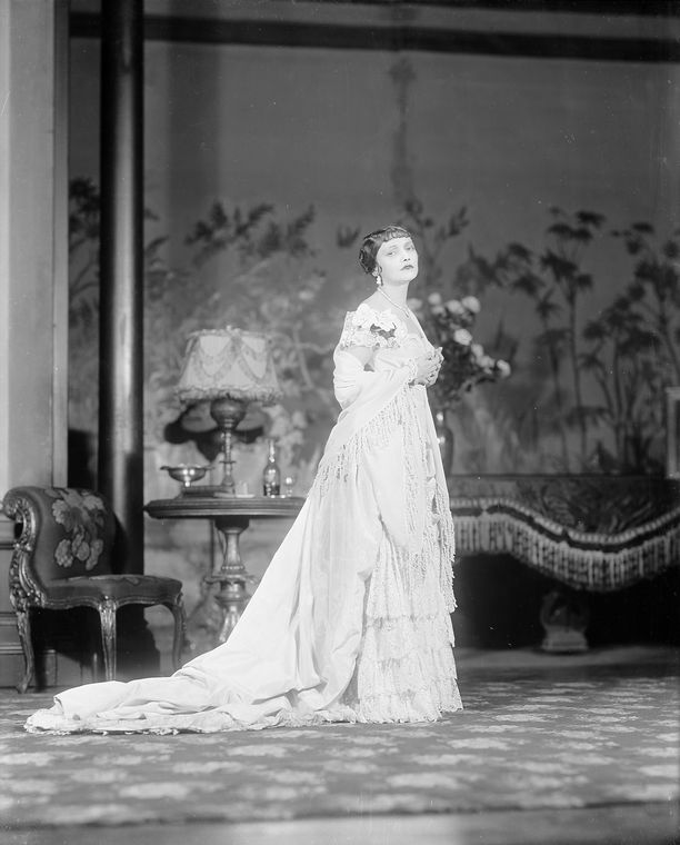 Black and white photograph. A woman wearing a long gown.