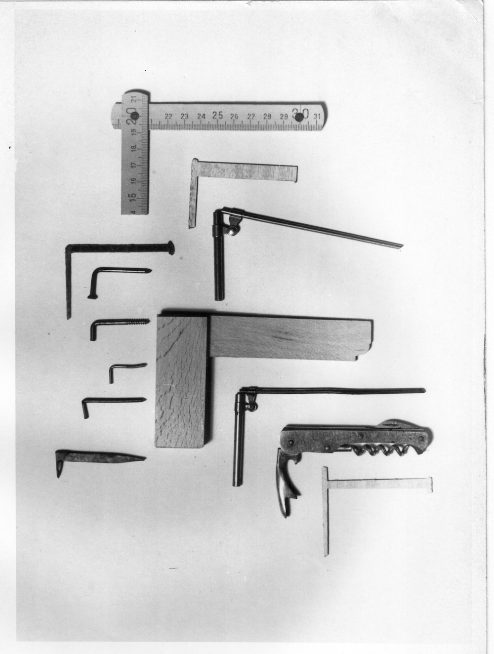 A black and white photograph showing a range of objects - a ruler, nails, wood - shaped into right angles.