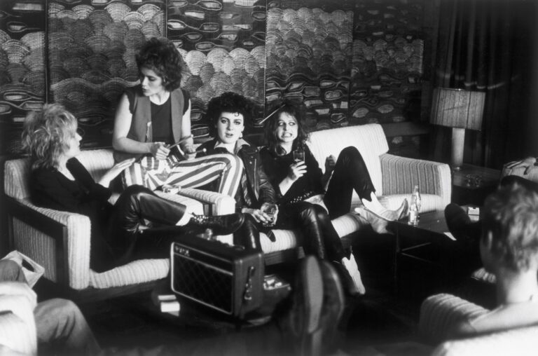 Black and white photograph. The band The Slits sit together on a sofa.
