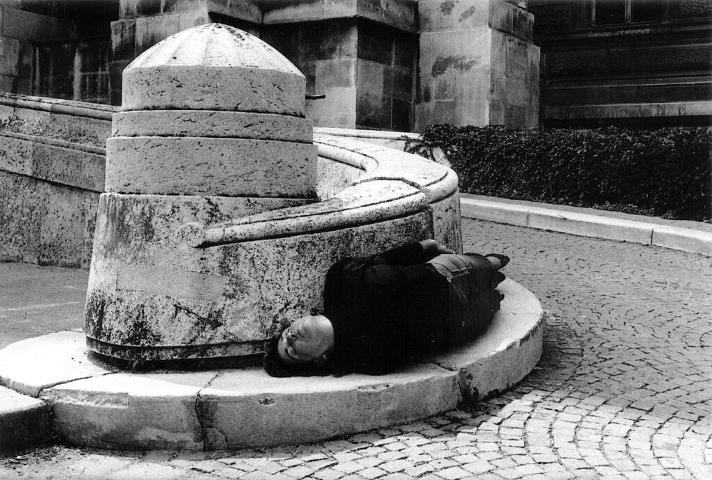 Black and white photo of a person lying around a pavement